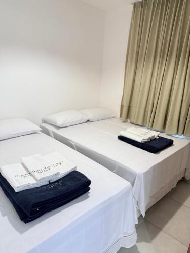 two beds in a room with white sheets and towels at Chalé da Barra EG in Barra Grande