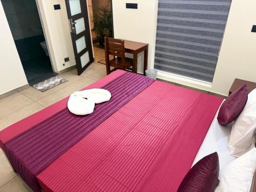 un lit violet avec deux serviettes blanches dessus dans l'établissement Casa Linda Residency, à Varkala