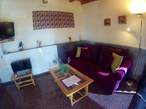 ein Wohnzimmer mit einem lila Sofa und einem Tisch in der Unterkunft Kleines Ferienhaus mit eigener, teils überdachter Terrasse in Alcalá