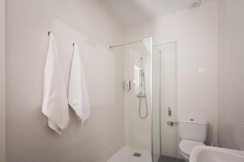 a white bathroom with a shower and a toilet at Hotel Rural Macondo in Trujillanos