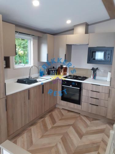 a kitchen with wooden cabinets and a stove top oven at Trekkers Rest, Brigham, Cockermouth, Cumbria in Cockermouth