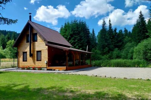 une petite maison en bois avec un grand porche dans l'établissement Czirják Kulcsosház, à Bucin