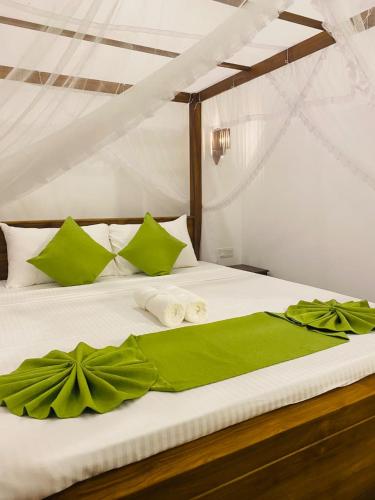 a bed with green and white sheets and pillows at Sithuka Villa Bentota in Bentota