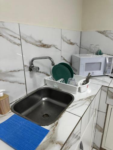 Una encimera de cocina con fregadero y microondas. en Hollywood Alojamiento, Apt 3, en Ciudad del Este