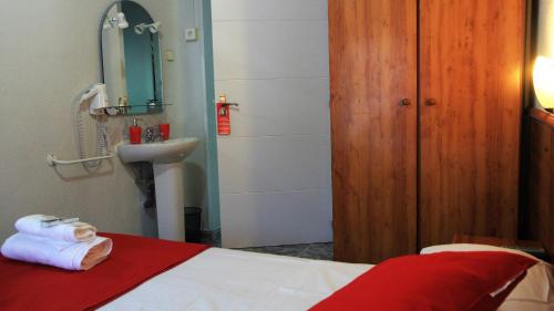 a bedroom with a bed and a sink and a mirror at Pension Antonio in Madrid