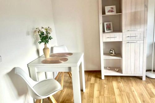 ein weißer Tisch und Stuhl mit einer Vase mit Blumen in der Unterkunft Das Haus mit Aussicht in Pirna