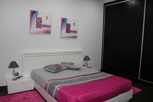 a bedroom with a large bed with a pink blanket at Vivenda Paraíso in Candelária