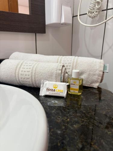 a bathroom with a towel and a bottle of oil on a table at Hotel Nossa Casa in Ijuí