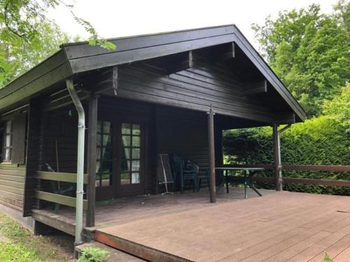 Cette cabine dispose d'une terrasse en bois avec une table. dans l'établissement Charmantes Ferienhaus Iris Im Waldecker Land, à Bad Arolsen