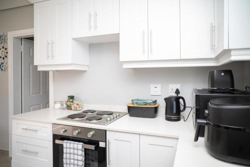 a kitchen with white cabinets and a stove top oven at Cosy Private cottages 3 bedroom salt pool DSTV in Durban