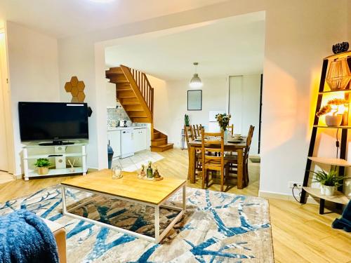 un salon avec une télévision et une table dans l'établissement Maison le B - Disneyland Paris - Parking - Wifi, à Bussy-Saint-Georges