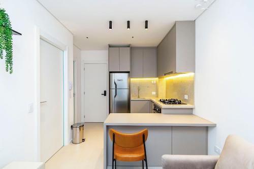 a kitchen with white cabinets and a counter and chairs at Apto em prédio com Piscina, Região Nobre - TEM0205 in Curitiba