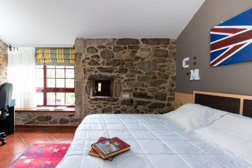 ein Schlafzimmer mit einem Bett und einer Steinwand in der Unterkunft Casa Dos Pazos in Brion