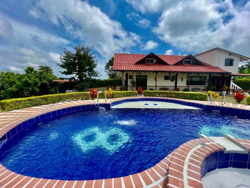 una piscina con acqua blu davanti a una casa di Casa Ulloa Eje Cafetero 30 Personas, Piscina & WiFi a Ulloa