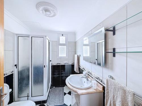 ein weißes Badezimmer mit Waschbecken und Dusche in der Unterkunft Apartamento Bela Vista in Estreito da Calheta