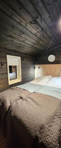 ein großes Bett in einem Zimmer mit Holzwänden in der Unterkunft Hytteparadis ved Neidenelva in Neiden