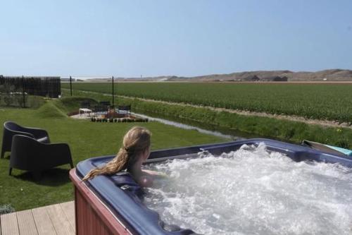 ein junges Mädchen in einem Whirlpool auf einem Feld in der Unterkunft Luxus-Villa, zu Fuß zum Strand, Dünenansicht mit privatem Whirlpool in Julianadorp