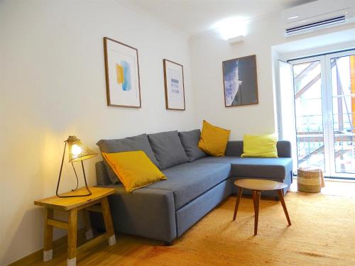 a living room with a blue couch and yellow pillows at Apartments Center Lisboa in Lisbon