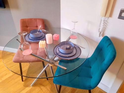 une table en verre avec une chaise bleue et une table en verre avec des assiettes dans l'établissement Modern 1BR - Leeds City Centre - Balcony Views, à Central Station