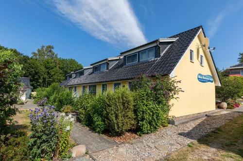 a yellow house with a black roof and some bushes at Ferienhaus Im Idyllischsten Winkel Rügens in Neuenkirchen