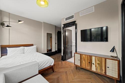 Un dormitorio con una cama y un televisor en la pared. en Freeman 303 by Rove - 1BR Condo with Shared Amenities, en Nueva York