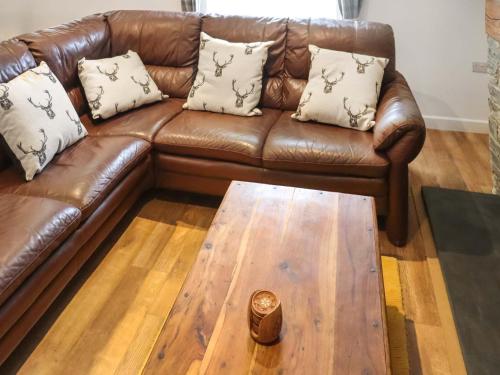 a brown leather couch with pillows and a wooden coffee table at Rhoshill in Llanfyrnach