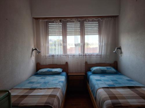 two beds in a room with a window at hotel monte castello II in Villa Gesell