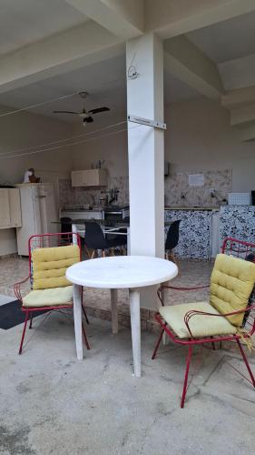 a white table and two chairs in a kitchen at O Paraiso é Aqui ! Casa de Hóspedes in Ubatuba