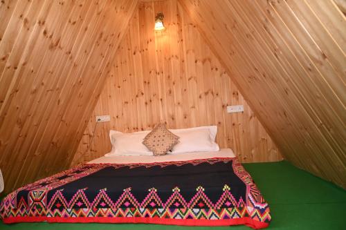 een bed in een kamer met een houten wand bij the clifton chapter tirthan in Banjār