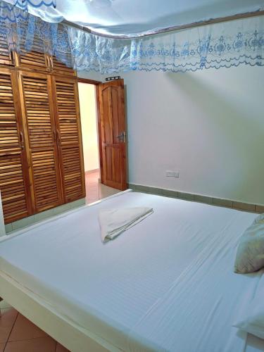 Una cama blanca con una toalla encima. en Evara staycation, en Shanzu