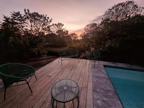 three chairs and a table on a wooden deck at Finca Cacao in Pavones