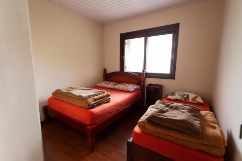 een kleine kamer met twee bedden en een raam bij Casa Joseph in Gramado