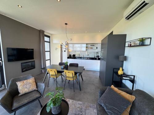 a living room with a table and chairs and a kitchen at Chalet Sonnenplätzchen Zweite Reihe Haus Nr 229 in Enkhuizen