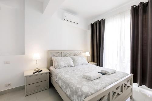 a white bedroom with a bed and a window at Great condo with pool in Punta Cana