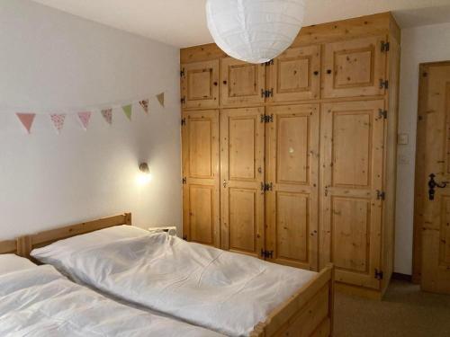 a bedroom with a bed with wooden cabinets and a chandelier at Chesa Muntanaia in Pontresina