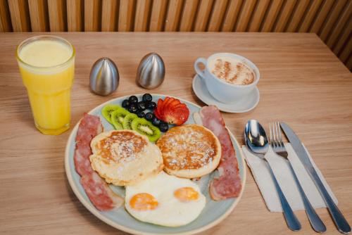 a breakfast plate with eggs bacon and fruit and a cup of coffee at 72Hub Apartments By Jalo in Bogotá