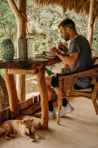 un hombre sentado en una mesa junto a un perro en Casa Caona, en El Valle