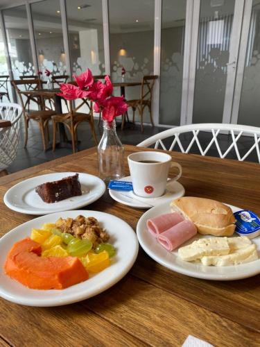uma mesa com pratos de comida e uma xícara de café em Samba Bossa Nova Cabo Frio em Cabo Frio