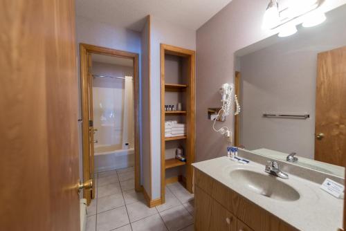 a bathroom with a sink and a mirror at Adirondack Retreat Inn & Suites in Lake George