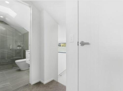 基督城2 Bedroom townhouse with garage close to Hagley Park, Westfield Mall, Railway Station, Hospital and Wolfbrook Arena的白色的浴室设有卫生间和玻璃门