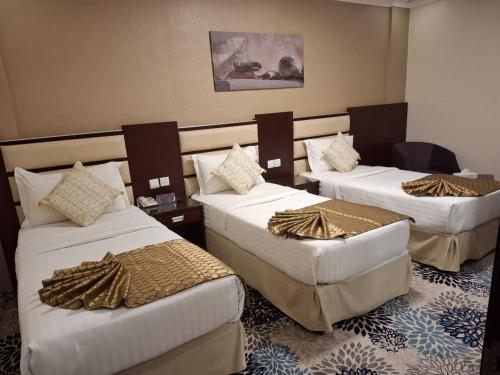 a hotel room with three beds in a room at Al JAWHRA TOWER HOTEL in Mecca