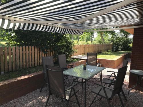 un patio avec une table et des chaises sous une pergola dans l'établissement Gemütliches Reetdachhaus In Schleswig Holstein, à Neuendorf-Sachsenbande