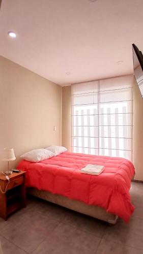 a large red bed in a room with a window at Apartamento JATUN MAMA in Chancay