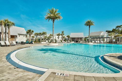a swimming pool with palm trees in a resort at Prominence Southside - Blue Skies in Watersound Beach