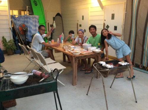 a group of people sitting around a wooden table at Shimanchu Guest House Yuien in Nanjo