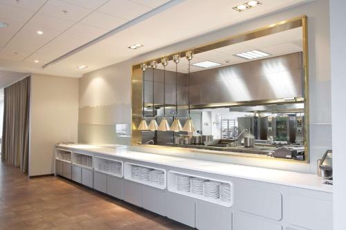 a restaurant with a counter with a large mirror at Scandic Sydhavnen in Copenhagen