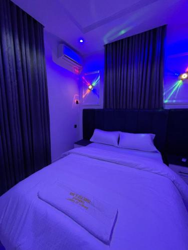 ein Schlafzimmer mit einem großen weißen Bett mit violetten Lichtern in der Unterkunft House of jessy in Iju