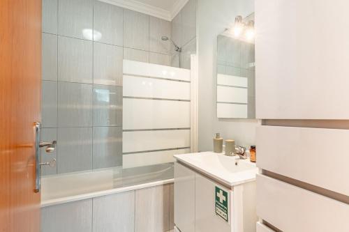 ein weißes Badezimmer mit Waschbecken und Dusche in der Unterkunft Brisa do Caniço in Caniço