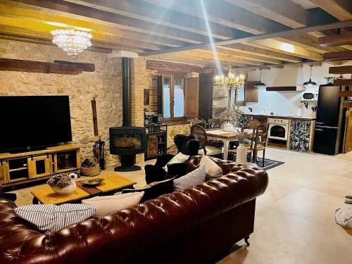 un salon avec un canapé en cuir brun et une télévision dans l'établissement BocallenaRural LASTRAS DE CUELLAR, à Lastras de Cuéllar