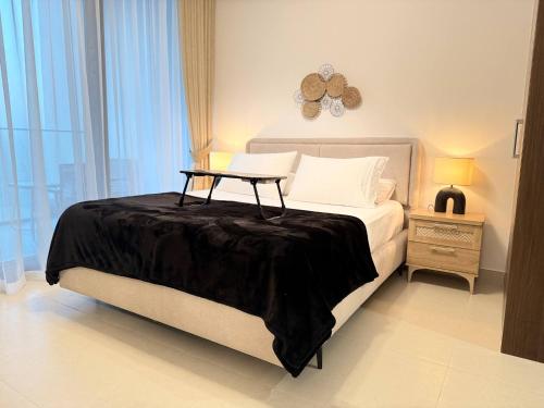 a bedroom with a bed with a table on it at ASHRI HH | Elegant 1BR in Ajmal Makan | Beachfront in Al Ḩamrīyah